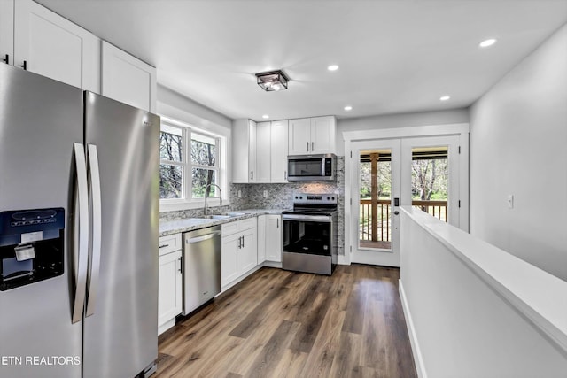 kitchen featuring tasteful backsplash, dark wood finished floors, a sink, stainless steel appliances, and white cabinetry