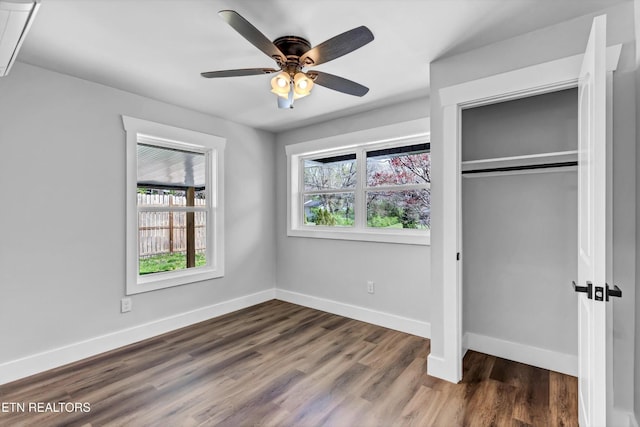 unfurnished bedroom featuring baseboards, a ceiling fan, dark wood finished floors, and a closet