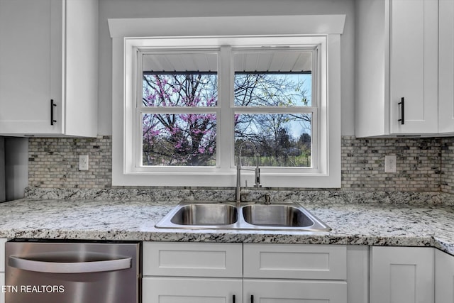 kitchen featuring decorative backsplash, a healthy amount of sunlight, white cabinetry, a sink, and dishwasher
