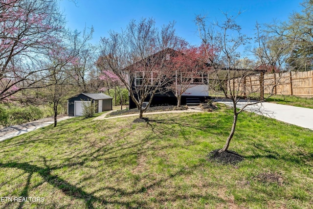 view of front of home with driveway, fence, an outdoor structure, and a front yard