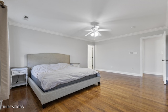 bedroom with baseboards, ornamental molding, and wood finished floors