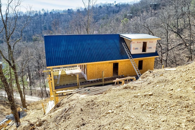 view of front of house with a forest view and metal roof
