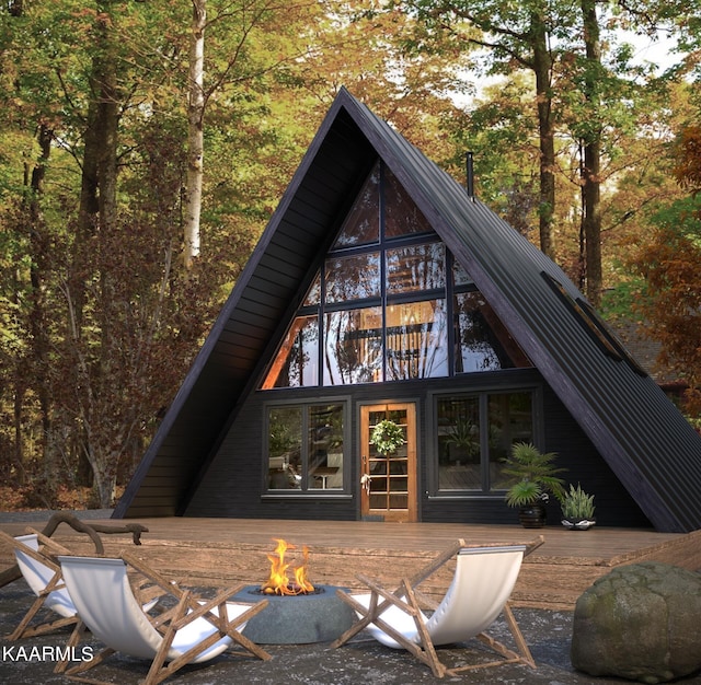 rear view of house with a wooden deck and an outdoor fire pit