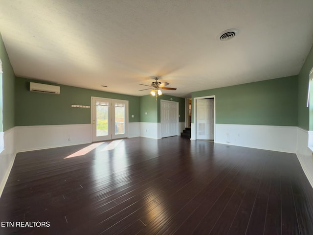 unfurnished room featuring ceiling fan, visible vents, a wainscoted wall, wood finished floors, and a wall mounted AC