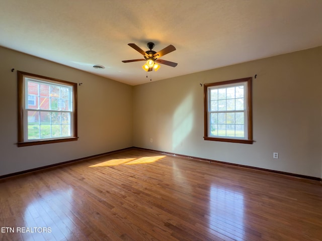 unfurnished room with baseboards, a healthy amount of sunlight, and hardwood / wood-style flooring
