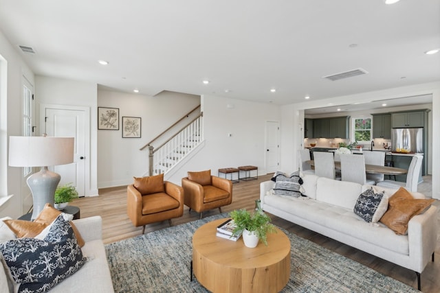 living area with visible vents, light wood-style flooring, stairs, and recessed lighting
