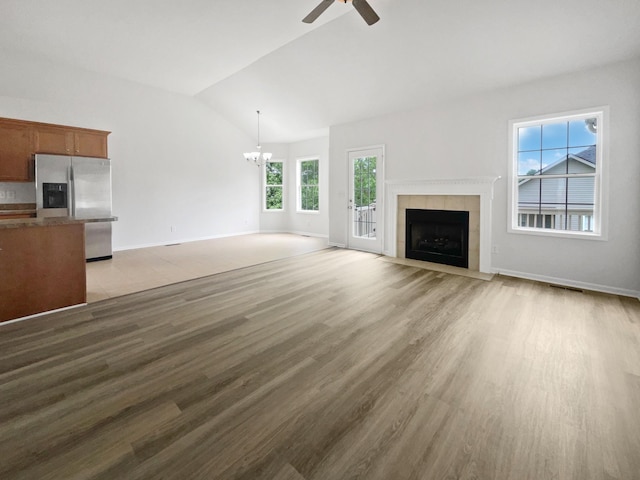 4013 Kristen St, Spring Hill, TN 37174 - unfurnished living room with a tiled fireplace, baseboards, ceiling fan with notable chandelier, light wood finished floors, and lofted ceiling
