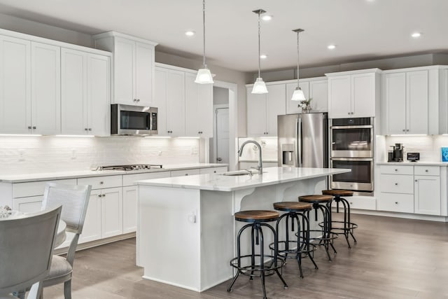5017 Great Falls Ct, College Grove, TN 37046 - kitchen featuring stainless steel appliances, a sink, decorative backsplash, a kitchen island with sink, and wood finished floors