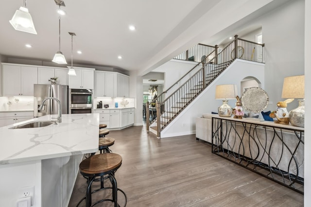 5017 Great Falls Ct, College Grove, TN 37046 - kitchen featuring a sink, stainless steel appliances, wood finished floors, white cabinets, and light stone counters