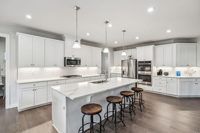5017 Great Falls Ct, College Grove, TN 37046 - kitchen with appliances with stainless steel finishes, a sink, tasteful backsplash, a center island with sink, and a breakfast bar