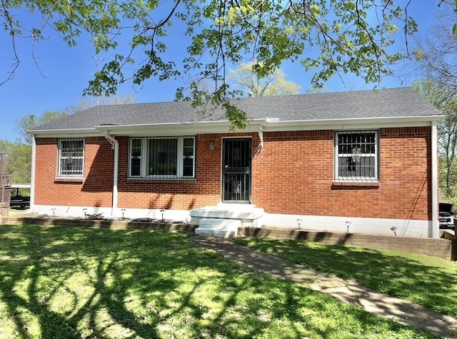 single story home featuring brick siding, a front yard, and roof with shingles
