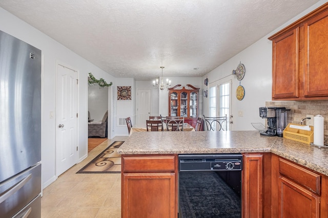kitchen with a notable chandelier, dishwasher, light countertops, freestanding refrigerator, and a peninsula