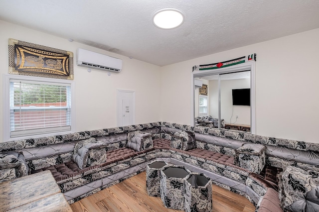 living room featuring a textured ceiling, a wall mounted AC, and wood finished floors