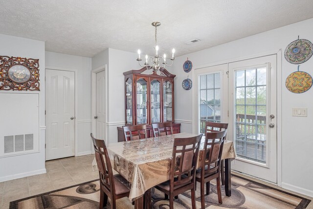 dining room with a textured ceiling, a chandelier, light tile patterned floors, and visible vents
