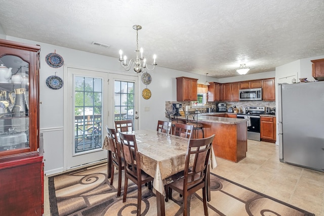 dining space featuring visible vents, a textured ceiling, and a chandelier