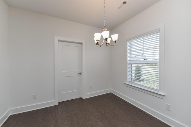 spare room with baseboards, a chandelier, dark wood finished floors, and visible vents