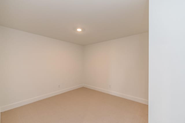 spare room featuring light colored carpet, recessed lighting, and baseboards