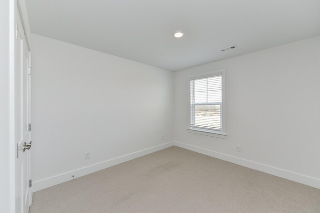 spare room featuring baseboards, visible vents, and light colored carpet