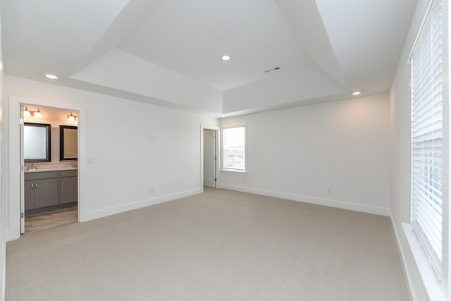 empty room featuring recessed lighting, light colored carpet, and a raised ceiling