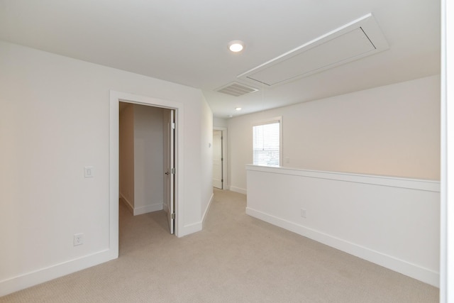 unfurnished room featuring baseboards, visible vents, light carpet, and attic access