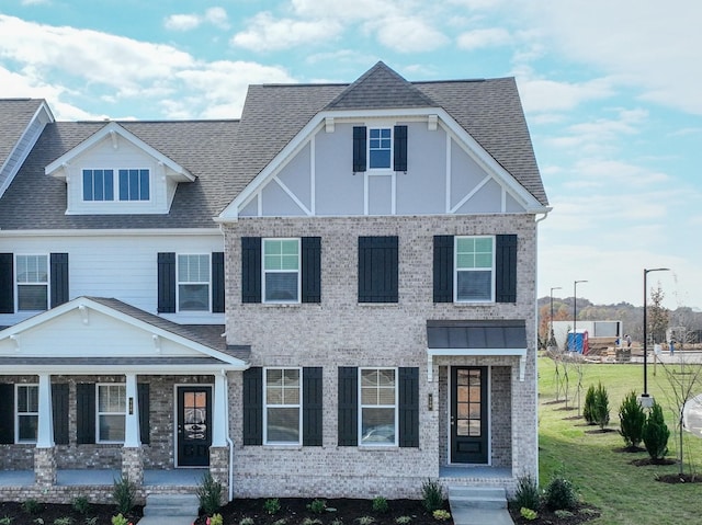 view of front of home with a porch, roof with shingles, and a front lawn