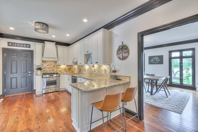 107 Churchill Farms Dr, Murfreesboro, TN 37127 - kitchen featuring ornamental molding, a peninsula, custom exhaust hood, stainless steel gas range oven, and light stone counters