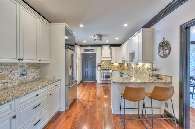 107 Churchill Farms Dr, Murfreesboro, TN 37127 - kitchen featuring a peninsula, wall chimney range hood, white cabinets, backsplash, and stainless steel appliances