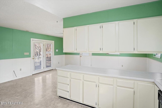 716 Lakewood Dr, Jefferson City, TN 37760 - kitchen with light countertops, a textured ceiling, a wainscoted wall, white cabinetry, and light floors