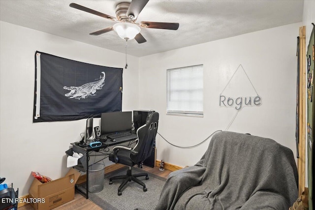 home office featuring a textured ceiling, ceiling fan, baseboards, and wood finished floors