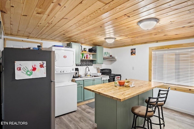 kitchen featuring freestanding refrigerator, black range with electric cooktop, butcher block counters, stacked washer and clothes dryer, and wood ceiling