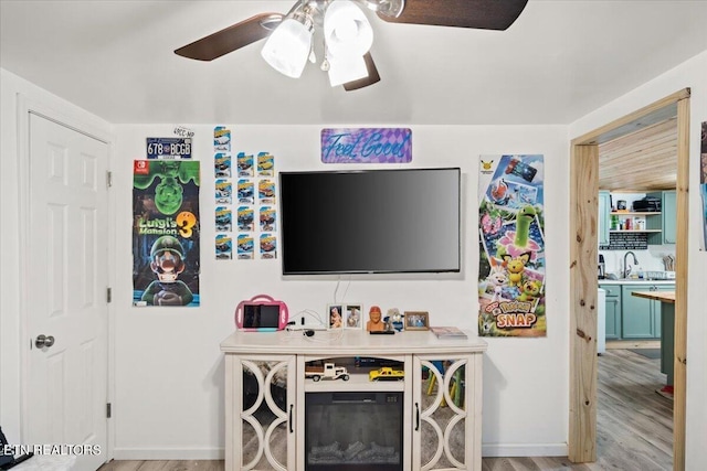 living area featuring baseboards, a ceiling fan, and light wood finished floors