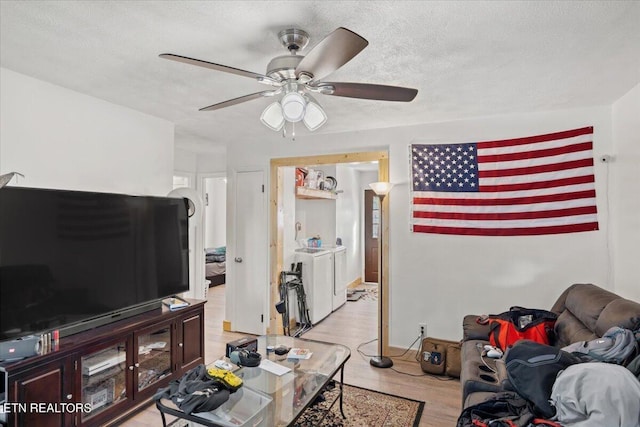living room with separate washer and dryer, a ceiling fan, light wood-style flooring, and a textured ceiling