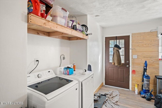 laundry room featuring laundry area, washer and clothes dryer, light wood-style floors, and a textured ceiling