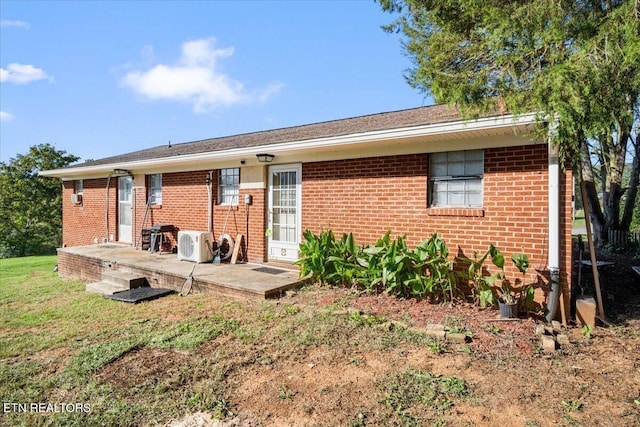 back of house featuring brick siding, ac unit, and a lawn