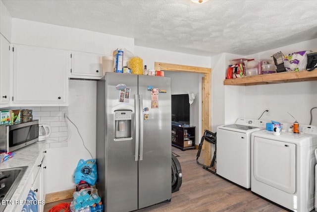kitchen featuring independent washer and dryer, light wood finished floors, light countertops, stainless steel appliances, and white cabinetry