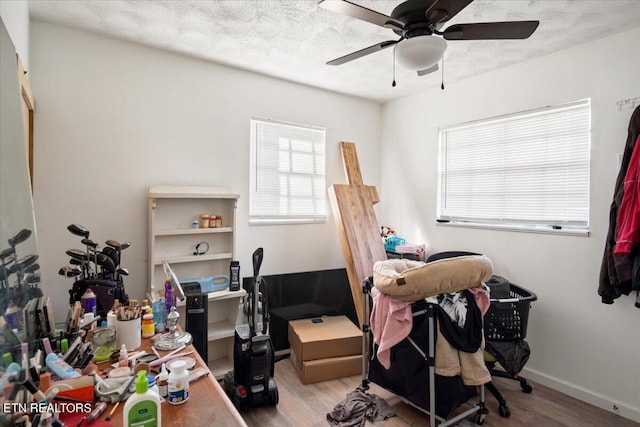 office space with a ceiling fan, baseboards, a healthy amount of sunlight, and wood finished floors