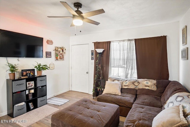 living area with baseboards, ceiling fan, and wood finished floors