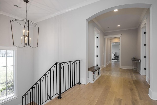 hallway with visible vents, baseboards, recessed lighting, arched walkways, and light wood finished floors