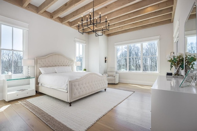 bedroom featuring an inviting chandelier, wood finished floors, and multiple windows