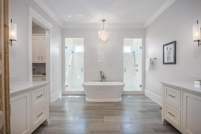 full bath with vanity, a freestanding bath, a stall shower, and a chandelier