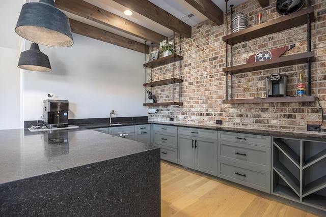 kitchen with open shelves, gray cabinetry, a sink, and beam ceiling