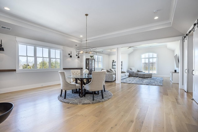 dining room featuring a barn door, light wood-style floors, recessed lighting, a tray ceiling, and visible vents