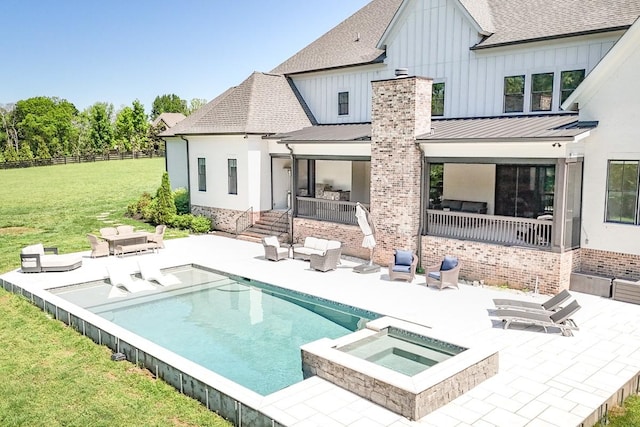 back of house featuring a standing seam roof, an in ground hot tub, a yard, and a patio area