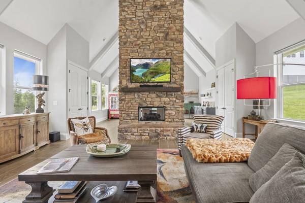 living area with a fireplace, wood finished floors, a wealth of natural light, and high vaulted ceiling