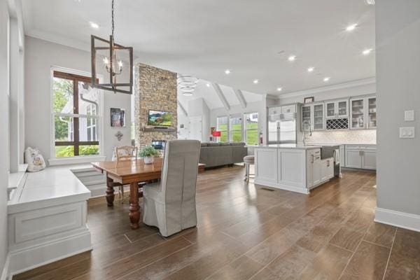 dining room with crown molding, an inviting chandelier, plenty of natural light, and lofted ceiling