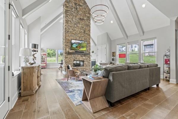 living area featuring an inviting chandelier, a fireplace, beam ceiling, and high vaulted ceiling