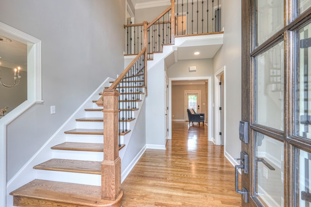 foyer entrance with stairs, baseboards, wood finished floors, and a high ceiling