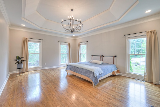 bedroom featuring an inviting chandelier, multiple windows, and a tray ceiling