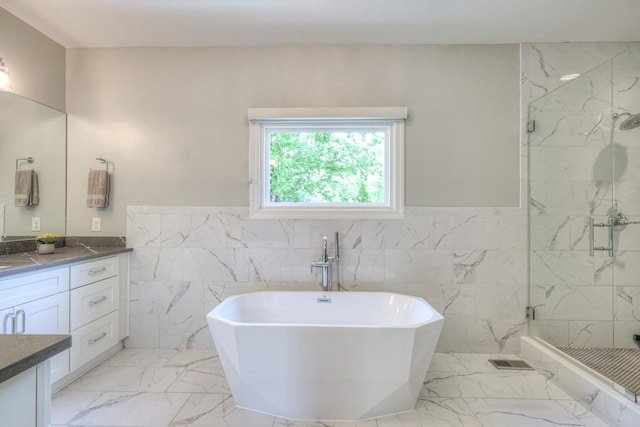full bath featuring tile walls, vanity, a marble finish shower, and marble finish floor
