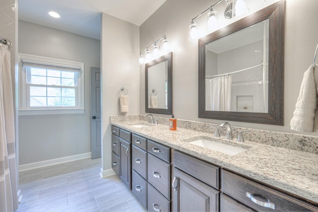 bathroom featuring baseboards, a sink, a shower with shower curtain, and double vanity